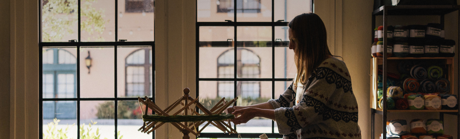 Woman in front of windows winding yarn