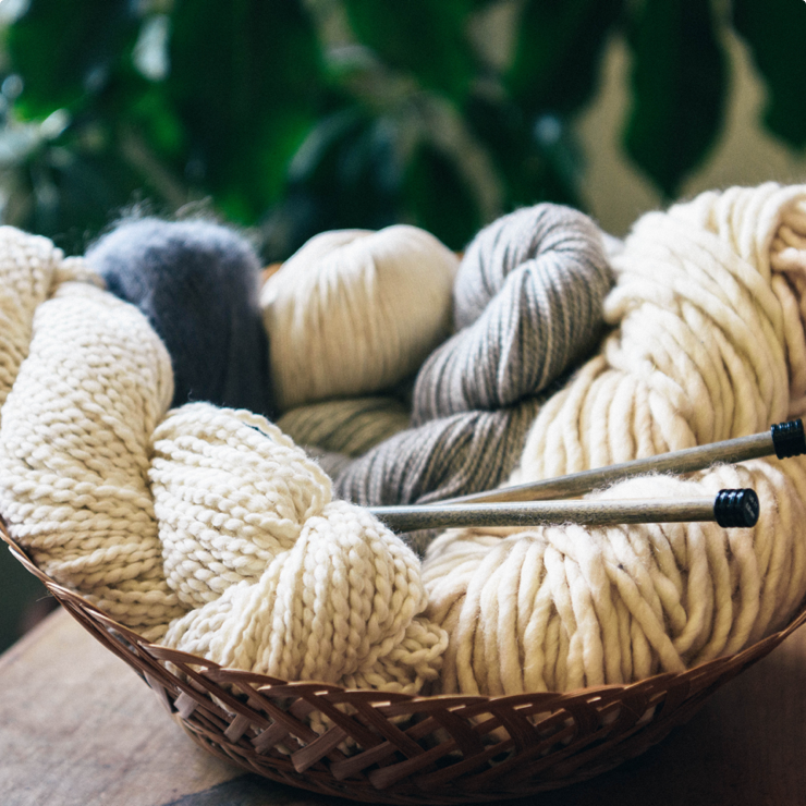 A wicker bowl of neutral colored yarn offered by Apricot Yarn & Supply